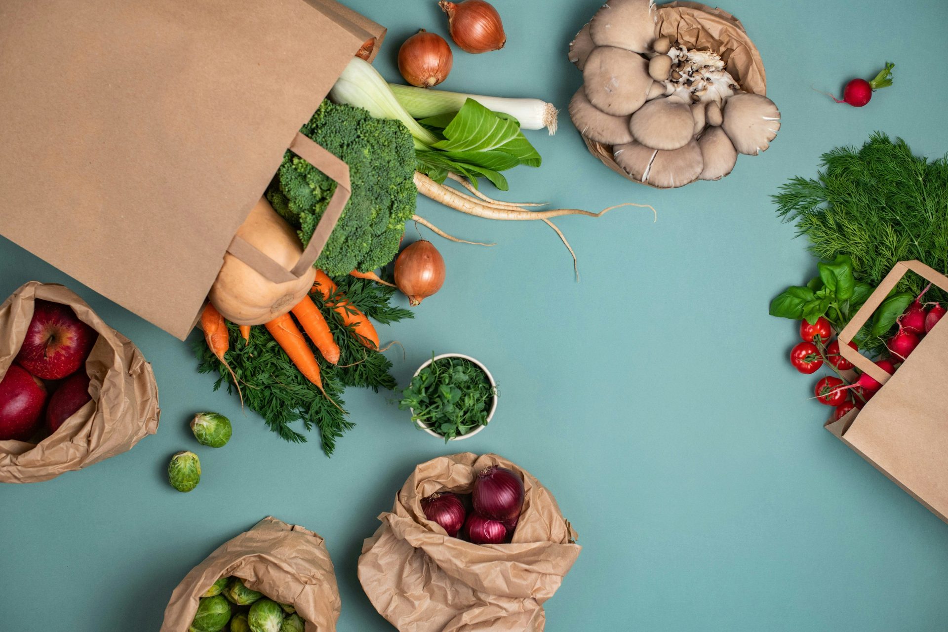 Una mesa cubierta de bolsas llenas de diferentes tipos de verduras.